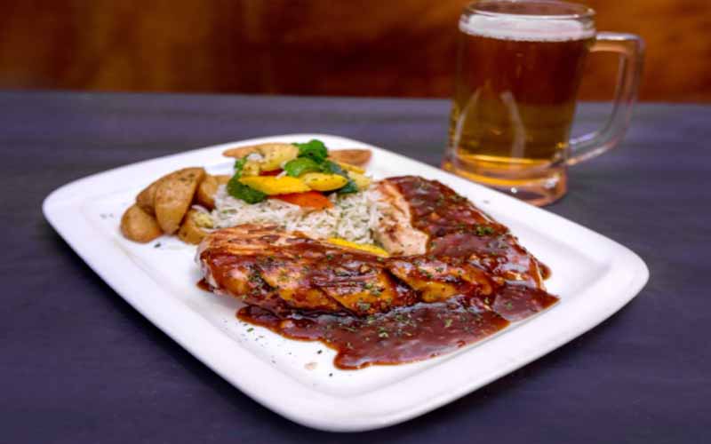 A plate of steak and potatoes next to a glass of beer