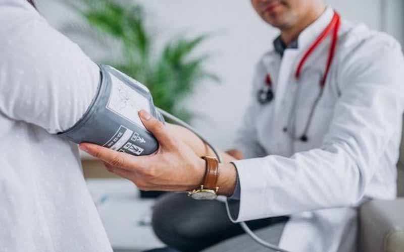 Doctor-holding-patient’s-arm-with-a-blood-pressure-monitor