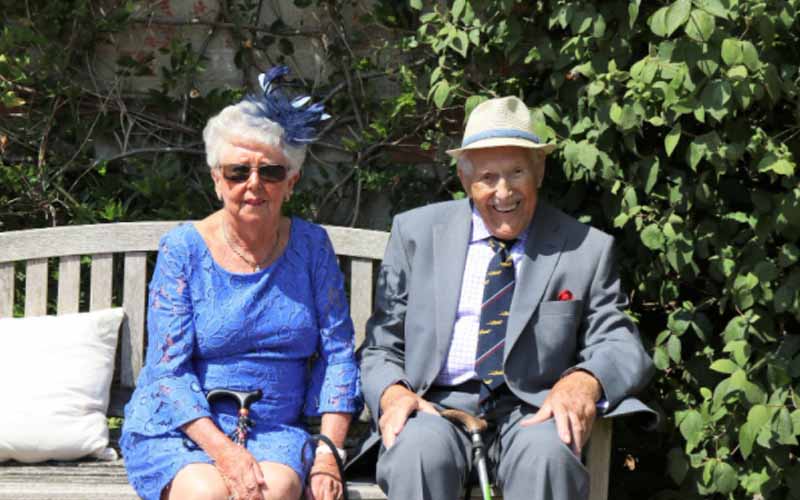 Elderly couple sitting outside on a wooden bench