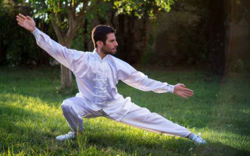 Man in white attire in a tai chi pose