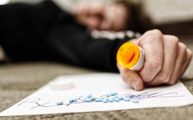 Man passed out holding a pill bottle