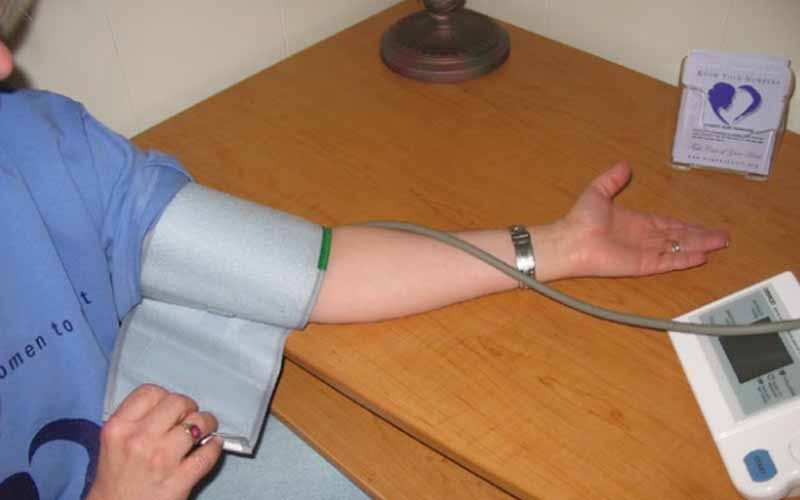 Patient-applying-blood-pressure-cuff-on-his-arm