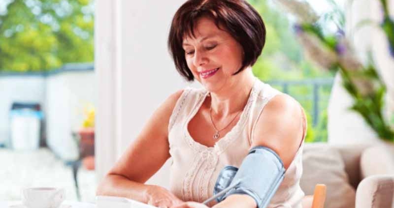 A woman measuring her blood pressure at home