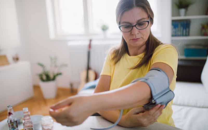 A woman placing her arm in a blood pressure arm cuff