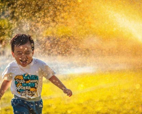 Child playing with water from sprinklers