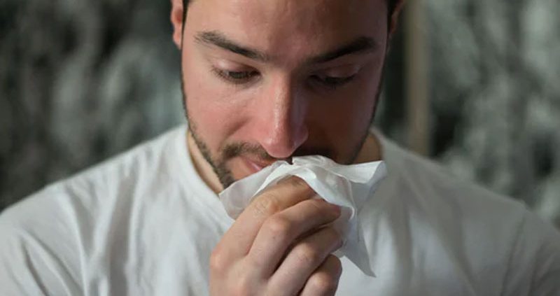 Man wiping his nose with a tissue